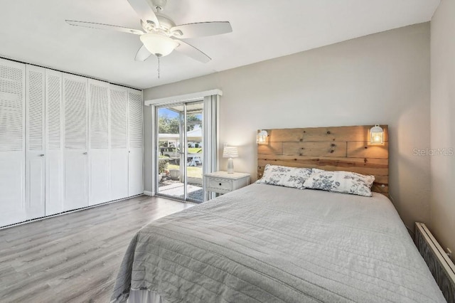 bedroom with a ceiling fan, wood finished floors, radiator heating unit, and access to exterior