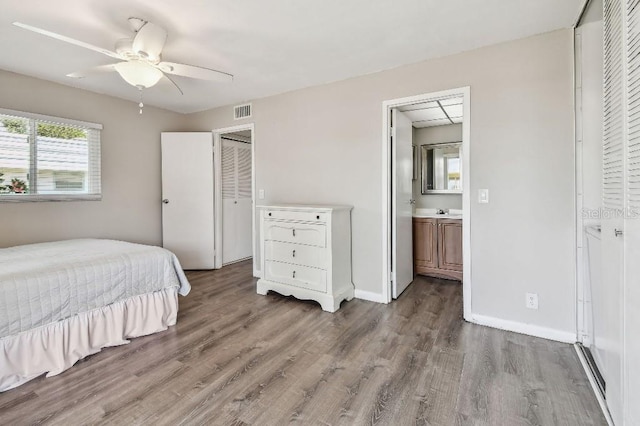 bedroom with visible vents, wood finished floors, baseboards, a closet, and connected bathroom