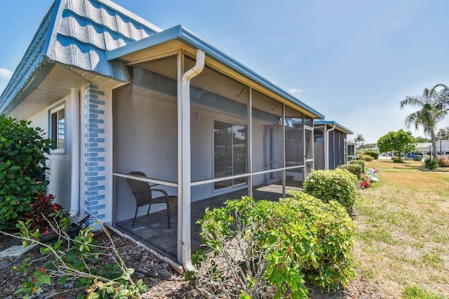view of home's exterior featuring a lawn and a sunroom