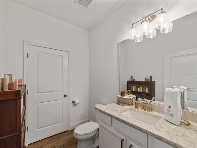 bathroom featuring visible vents, wood finished floors, toilet, and vanity