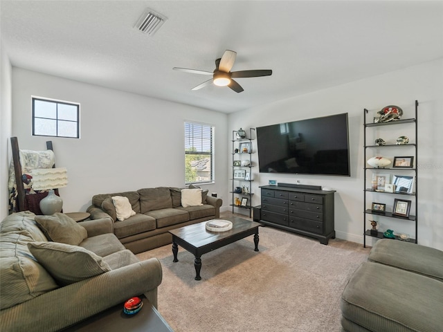 carpeted living area with visible vents, baseboards, ceiling fan, and a wealth of natural light