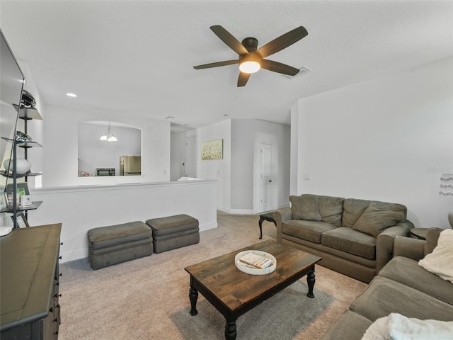carpeted living room with baseboards, ceiling fan with notable chandelier, and visible vents
