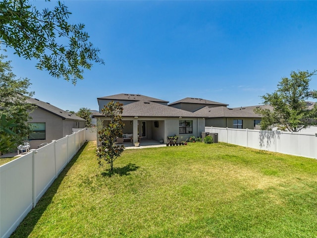 rear view of house with a lawn, a fenced backyard, a patio area, and stucco siding