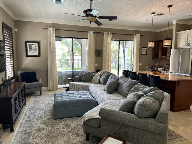 living room with plenty of natural light, a ceiling fan, a textured ceiling, and visible vents