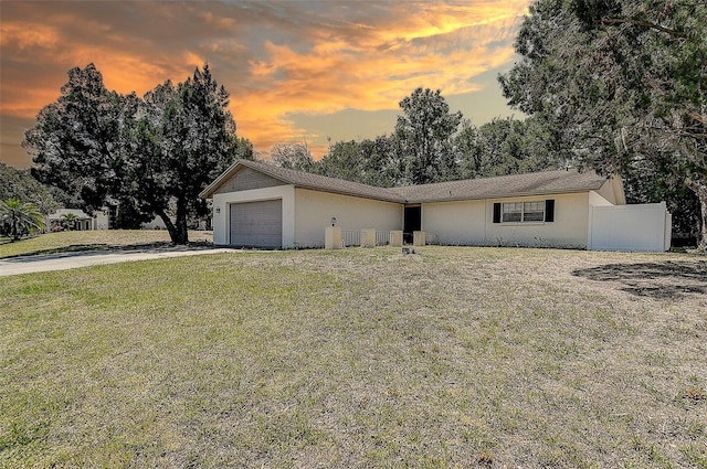 view of front of house with fence, a garage, stucco siding, concrete driveway, and a lawn