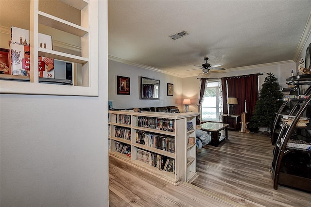 interior space featuring crown molding, a textured ceiling, visible vents, and wood finished floors