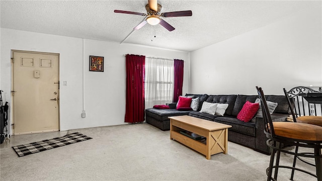living area with light carpet, a ceiling fan, and a textured ceiling