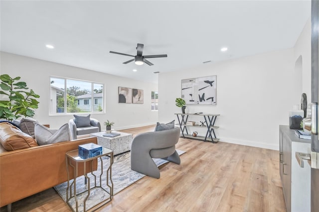 living room featuring light wood-type flooring, a ceiling fan, arched walkways, baseboards, and recessed lighting
