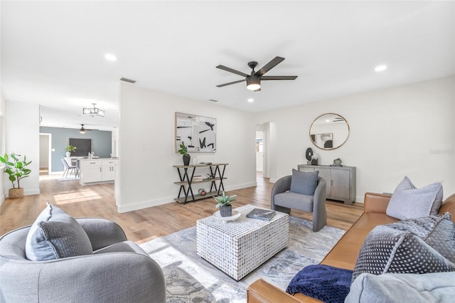 living area featuring arched walkways, a ceiling fan, light wood finished floors, recessed lighting, and baseboards