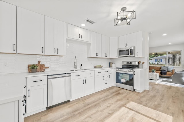 kitchen with stainless steel appliances, a sink, light countertops, white cabinets, and recessed lighting