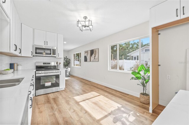 kitchen with stainless steel appliances, light countertops, light wood-style floors, and backsplash