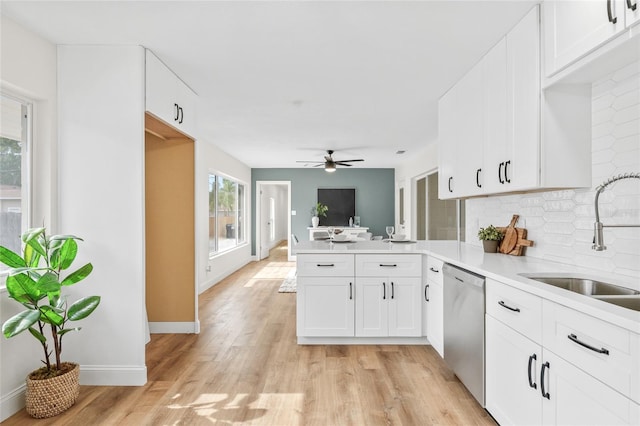kitchen with stainless steel dishwasher, a sink, a peninsula, decorative backsplash, and ceiling fan
