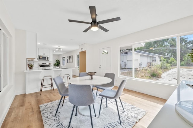 dining area with light wood-style floors, baseboards, and a ceiling fan