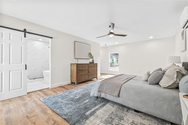 bedroom with light wood-style floors, a barn door, recessed lighting, a wall mounted air conditioner, and a ceiling fan