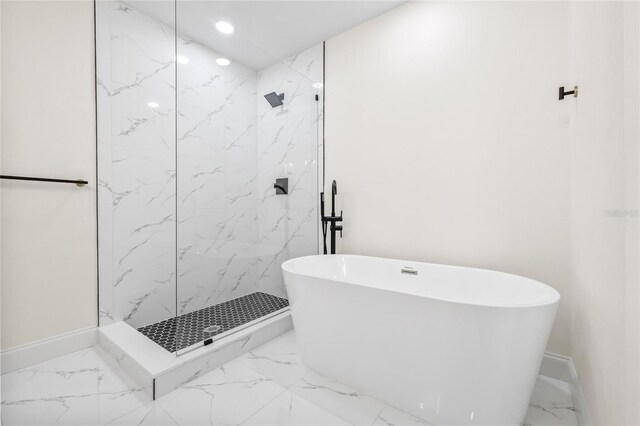 full bath featuring marble finish floors, a marble finish shower, a soaking tub, and baseboards