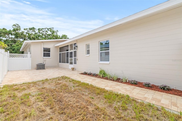 rear view of property with a patio area, central air condition unit, and a sunroom