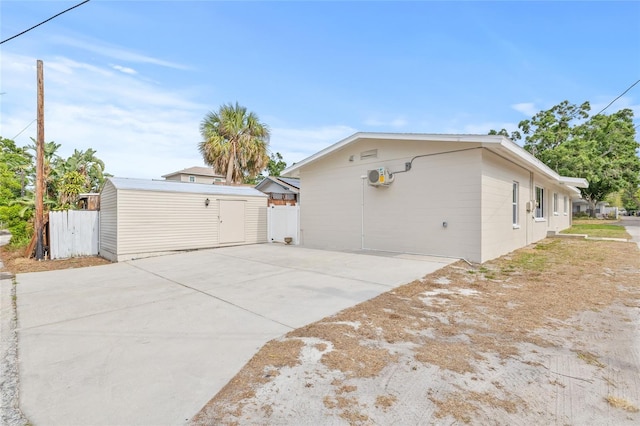 view of side of property with a storage unit, an outbuilding, driveway, and fence
