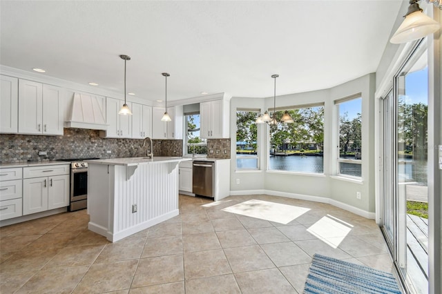 kitchen featuring light tile patterned floors, premium range hood, stainless steel appliances, and a wealth of natural light