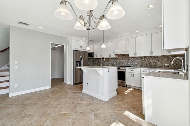 kitchen featuring decorative backsplash, visible vents, appliances with stainless steel finishes, a sink, and custom range hood