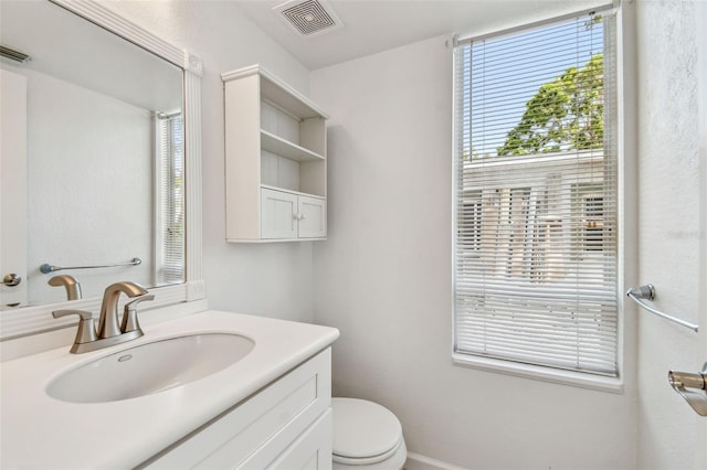 bathroom with toilet, visible vents, and vanity