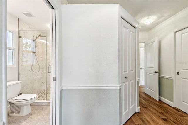 bathroom with visible vents, a marble finish shower, wood finished floors, and toilet