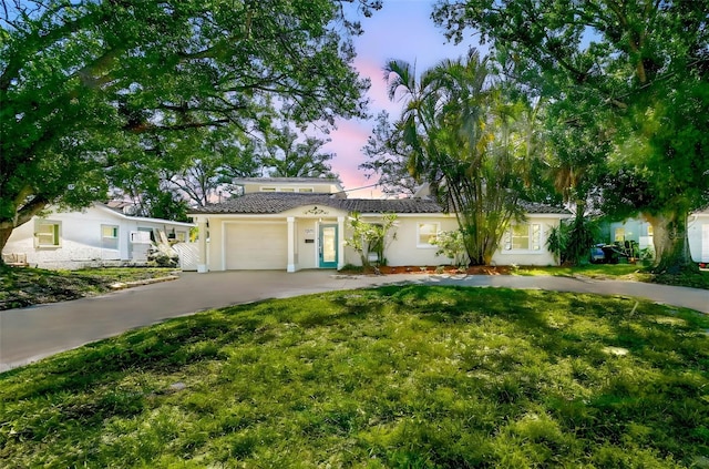 single story home with a tiled roof, stucco siding, driveway, and a garage