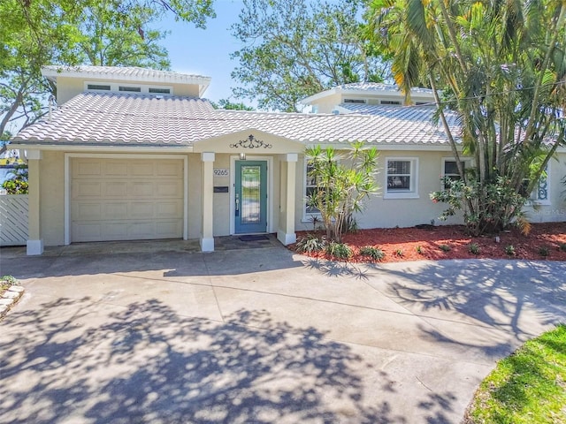 view of front of home featuring an attached garage, concrete driveway, stucco siding, and a tile roof