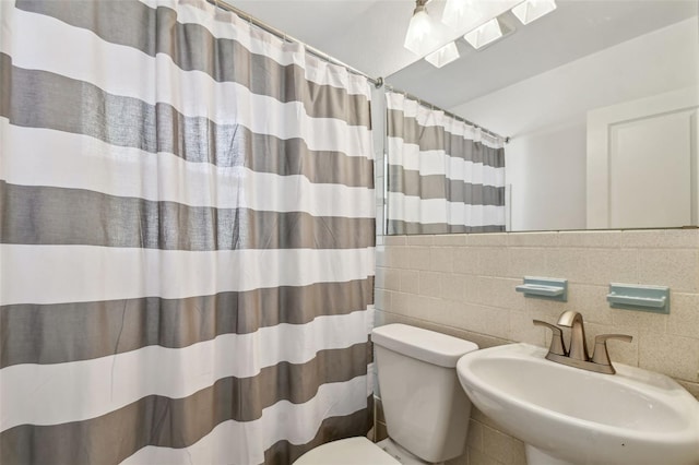 bathroom featuring a shower with curtain, a skylight, tile walls, a sink, and toilet