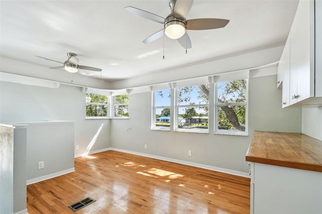 interior space featuring ceiling fan, visible vents, baseboards, and light wood finished floors