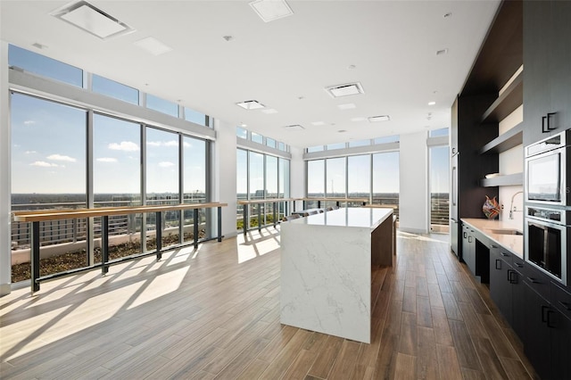 777 3rd Ave N Unit 1403, Saint Petersburg, FL 33701 - kitchen with open shelves, dark cabinets, a center island, wood finished floors, and expansive windows