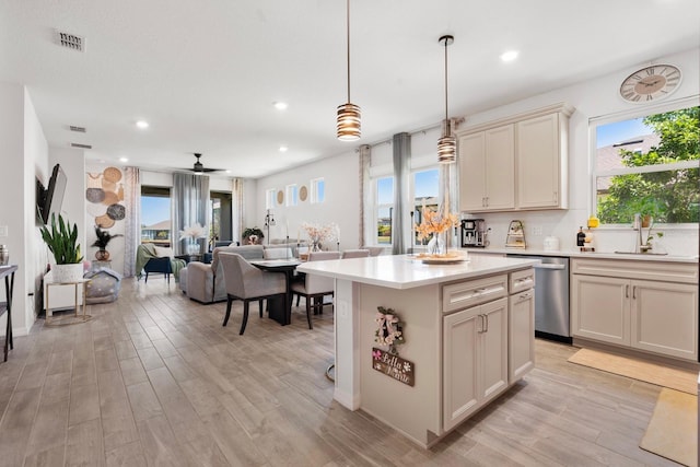 kitchen with a sink, stainless steel dishwasher, light wood-style flooring, and visible vents