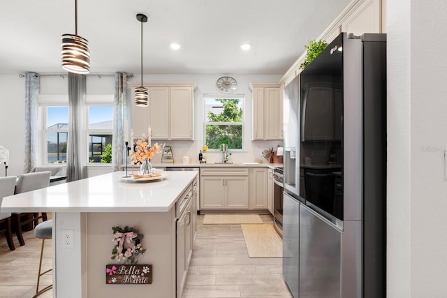 kitchen featuring refrigerator with glass door, a breakfast bar, recessed lighting, light countertops, and light wood-style flooring