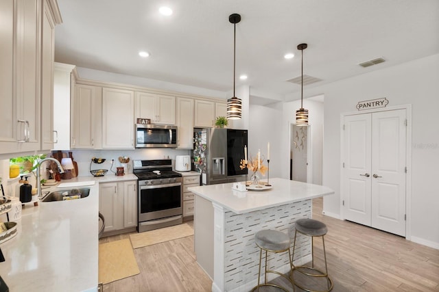 kitchen with a sink, light wood-style floors, stainless steel appliances, and visible vents