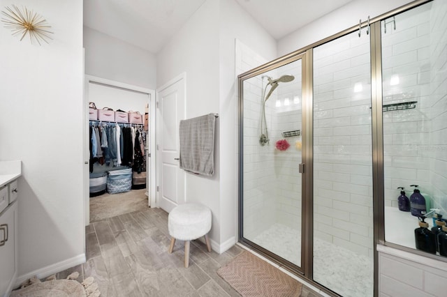 bathroom with vanity, a stall shower, and a walk in closet