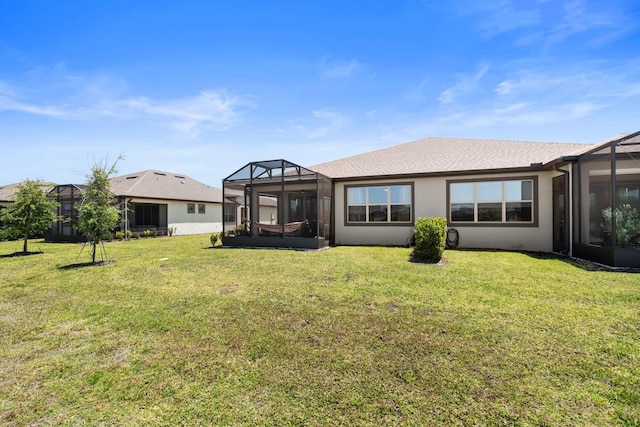 back of house featuring a lawn, glass enclosure, roof with shingles, and stucco siding