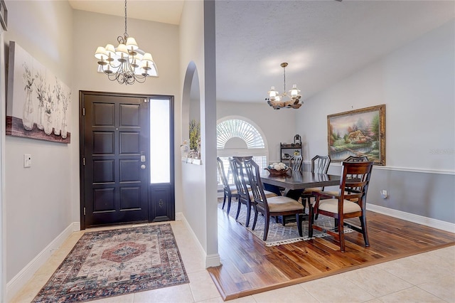 entryway with an inviting chandelier, arched walkways, and tile patterned flooring