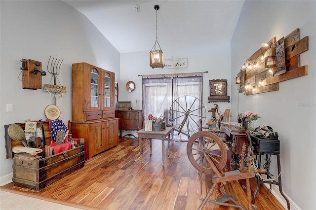 entryway with baseboards, wood finished floors, and high vaulted ceiling