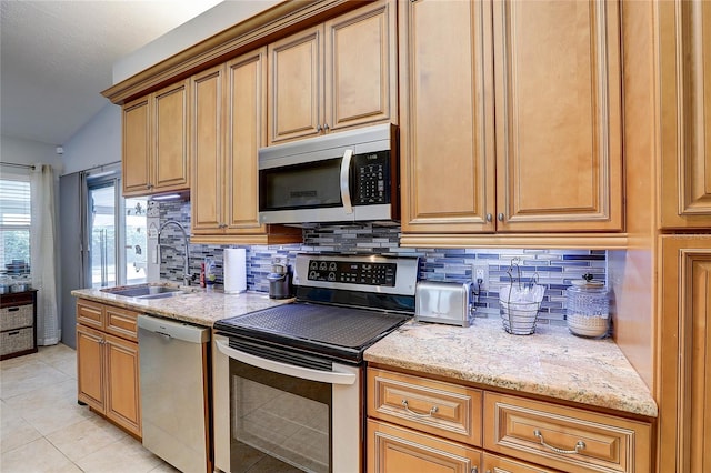 kitchen with a sink, appliances with stainless steel finishes, light tile patterned floors, and backsplash