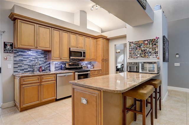kitchen featuring light stone counters, a sink, backsplash, vaulted ceiling, and stainless steel appliances