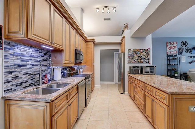 kitchen with backsplash, visible vents, a sink, light stone counters, and stainless steel appliances