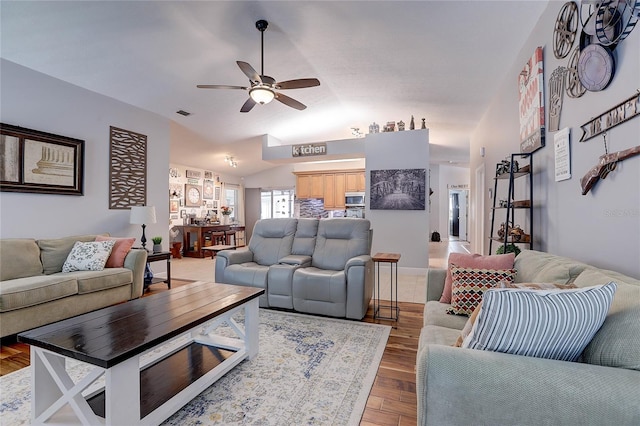 living room featuring visible vents, light wood finished floors, ceiling fan, and vaulted ceiling