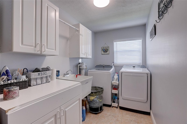 laundry room featuring light tile patterned flooring, baseboards, a textured ceiling, cabinet space, and independent washer and dryer