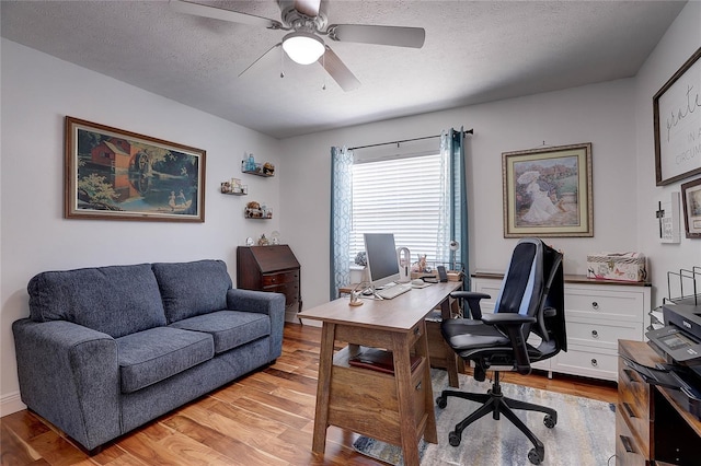 office area featuring light wood-style floors, ceiling fan, and a textured ceiling