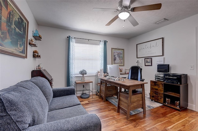 office space with ceiling fan, a textured ceiling, light wood-style flooring, baseboards, and visible vents