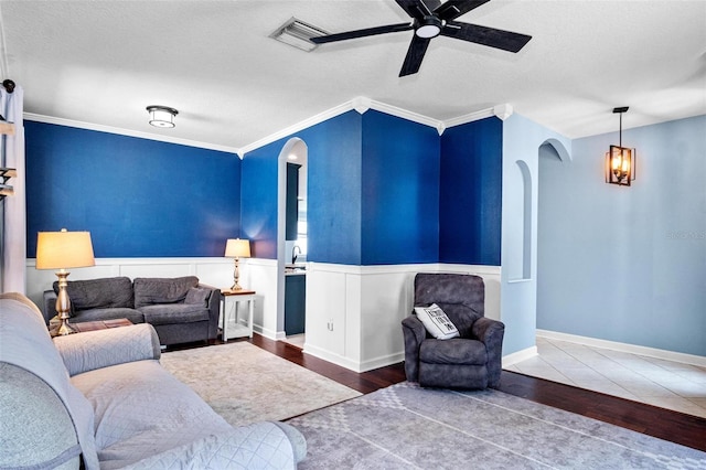 living room featuring arched walkways, wainscoting, ceiling fan, and wood finished floors