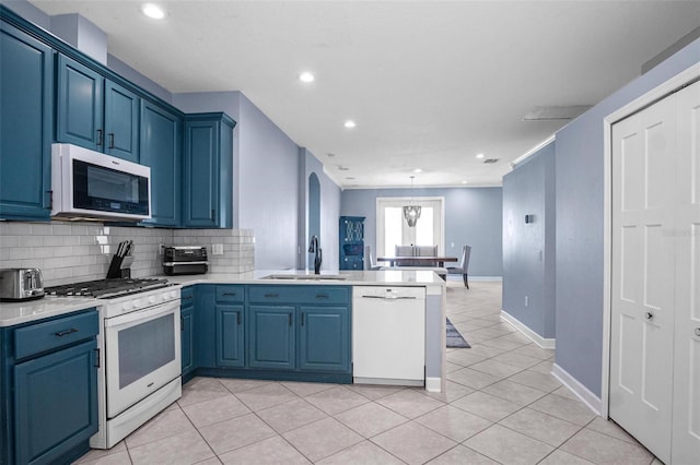 kitchen featuring decorative backsplash, blue cabinets, a sink, a peninsula, and white appliances