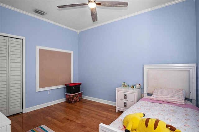 bedroom featuring crown molding, baseboards, wood finished floors, visible vents, and a closet