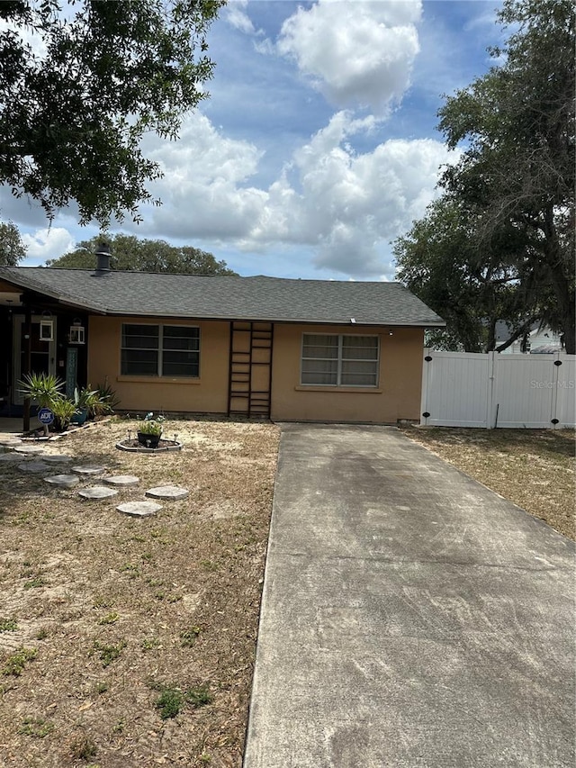 ranch-style house with fence, a gate, roof with shingles, and stucco siding