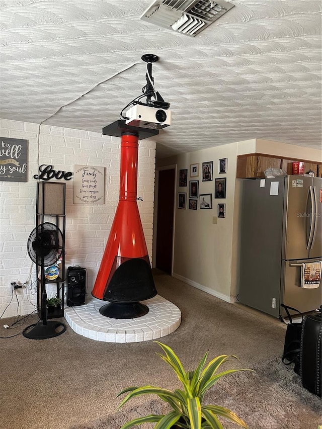 recreation room featuring baseboards, carpet, a wood stove, and visible vents
