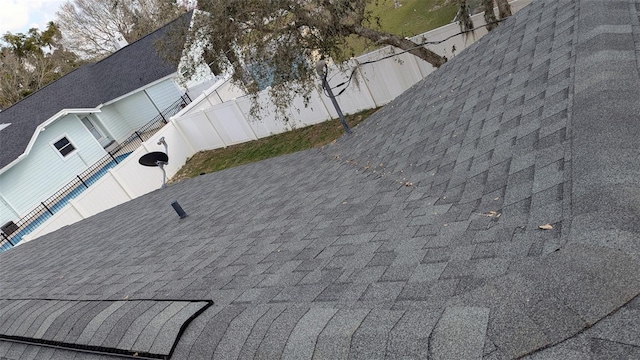 details featuring fence and a shingled roof